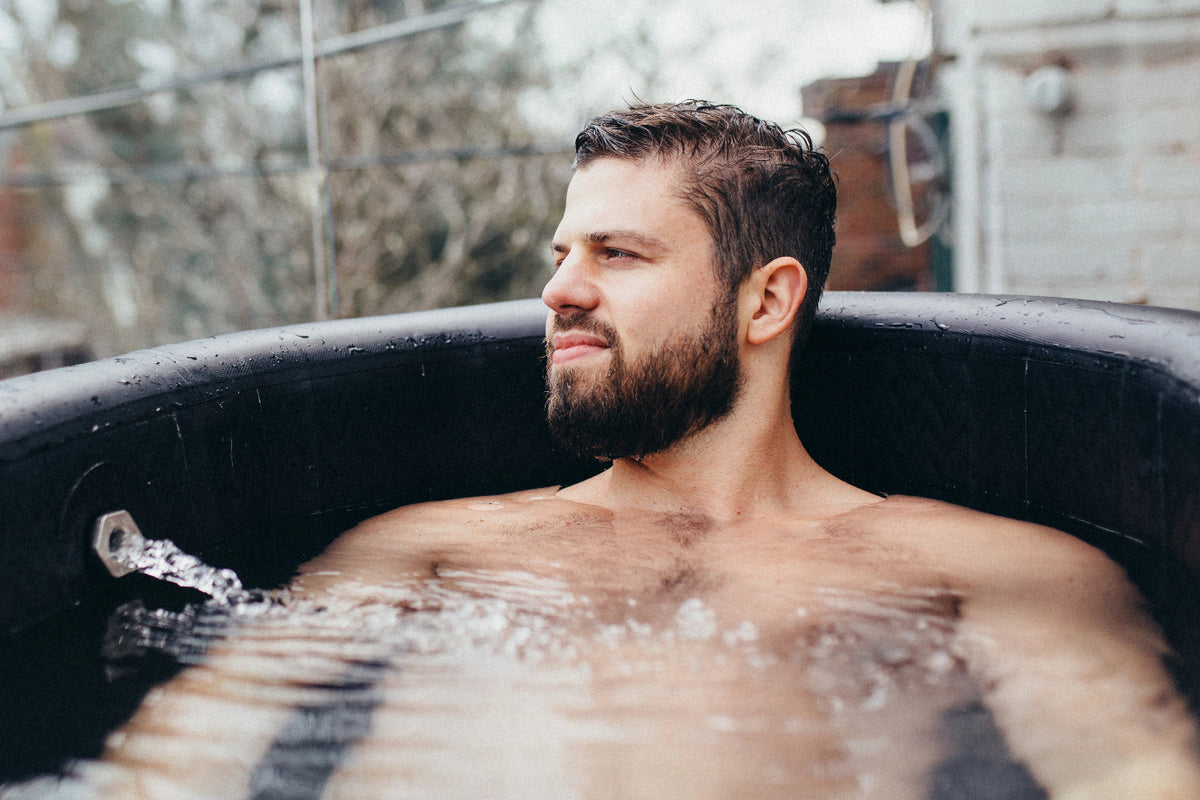 Man relaxing in a cold tub outdoors with a blurred background