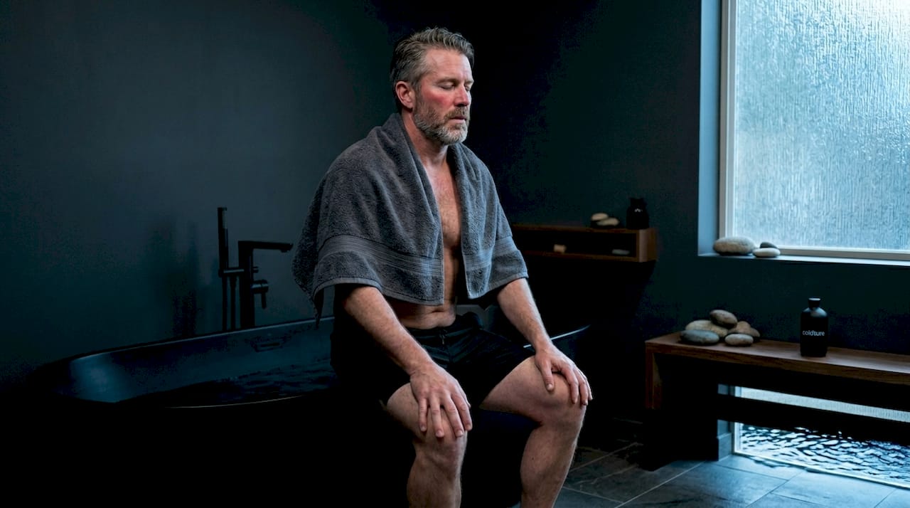 Man practicing breathwork beside cold plunge tub
