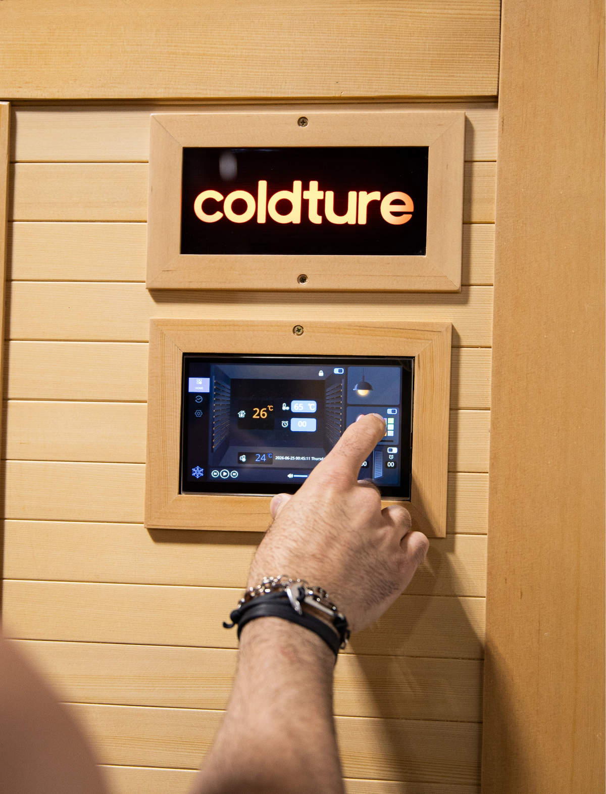 Person interacting with a digital display on a wooden wall, featuring the brand 'coldture'.